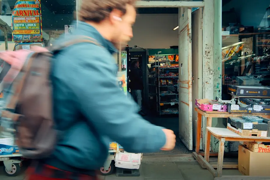 A person with a backpack walks past an open shop door; colorful signs and goods are displayed outside, with shelves and products visible inside the store.